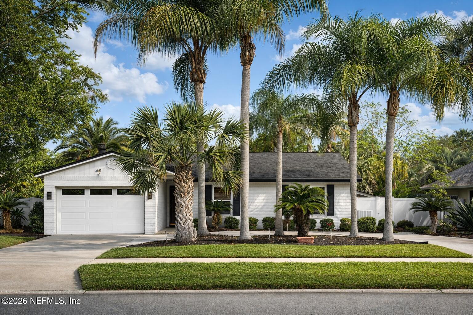a view of a white house with a large tree and a yard in front of it