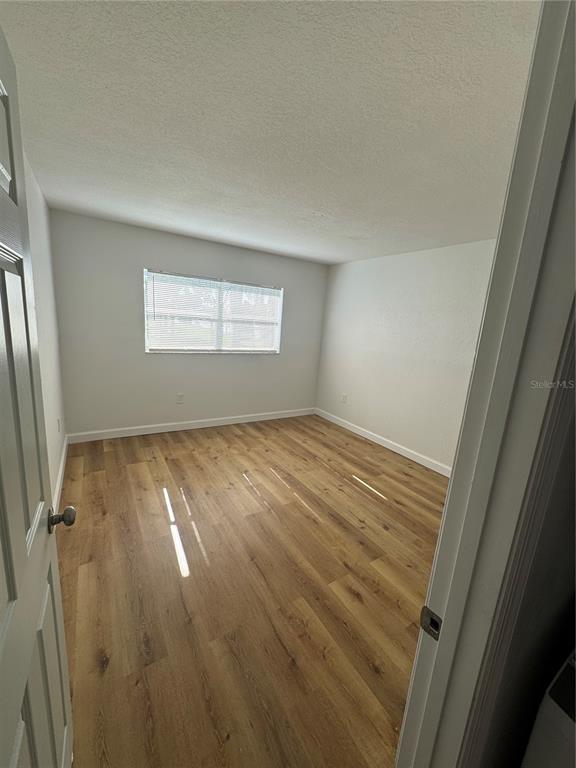 9919 Aquarius Drive, Unit 6 Port Richey, FL 34668 - Photo 8 of 25 a view of empty room with wooden floor and fan