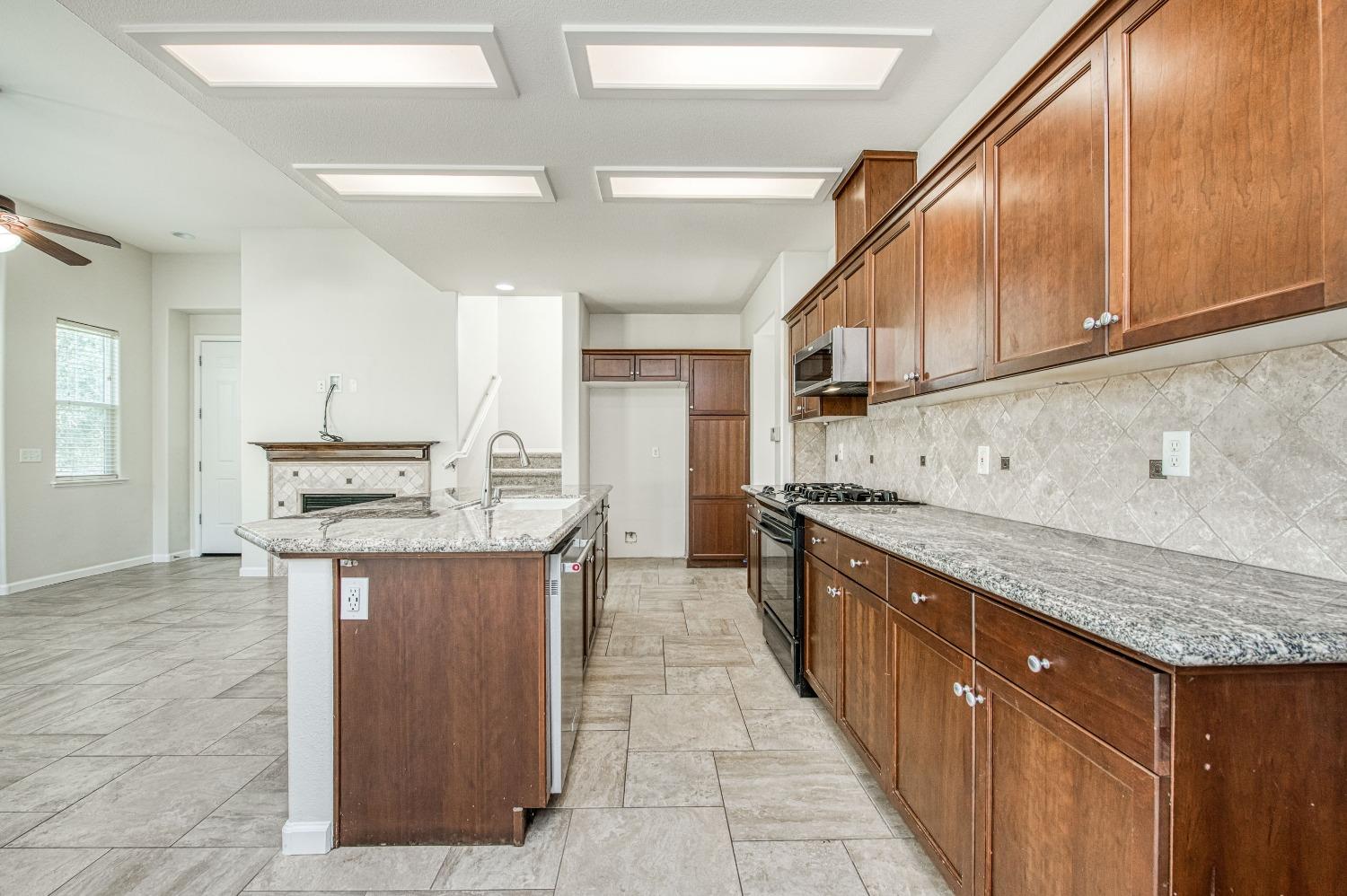 3991 Harlan Ranch Boulevard Clovis, CA 93619 - Photo 3 of 21 a kitchen with stainless steel appliances granite countertop a sink stove and cabinets
