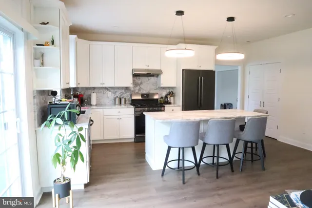a kitchen with stainless steel appliances kitchen island granite countertop a table chairs and a refrigerator