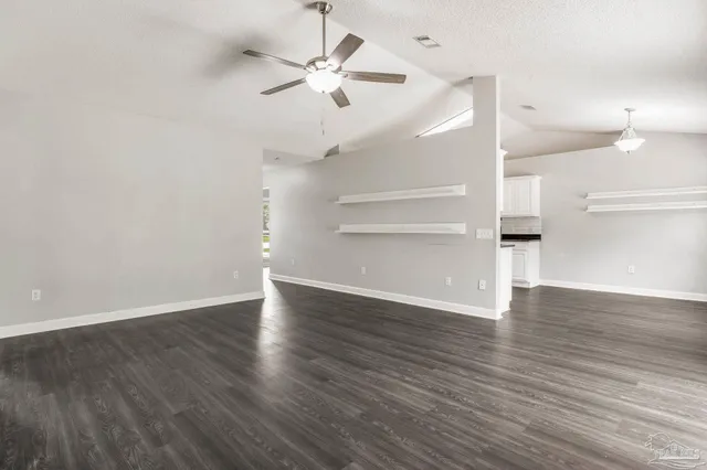 an empty room with wooden floor ceiling fan and windows