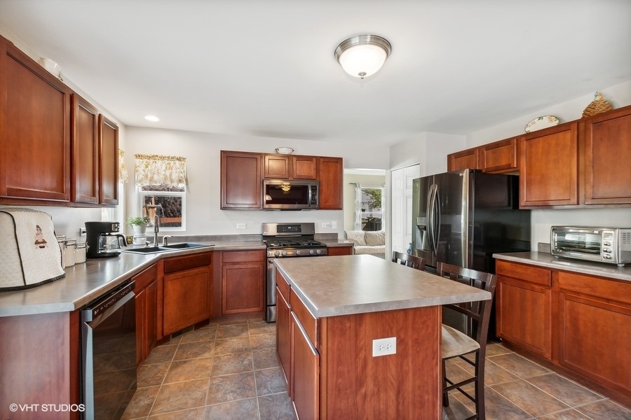 1417 Roth Drive Joliet, IL 60431 - Photo 4 of 18 a kitchen with stainless steel appliances granite countertop wooden cabinets a stove top oven a sink and dishwasher