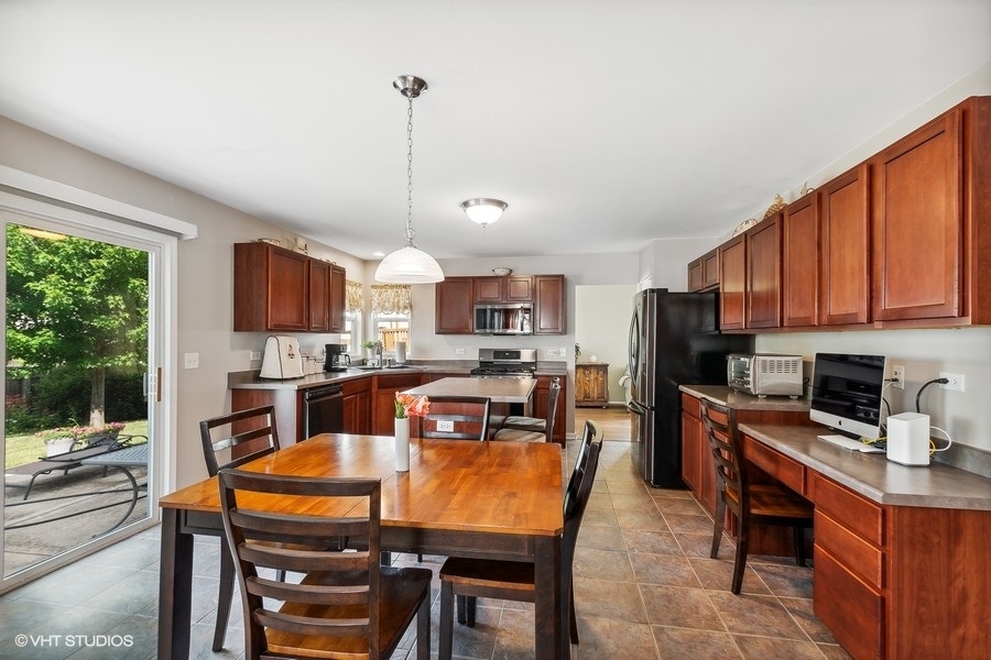 1417 Roth Drive Joliet, IL 60431 - Photo 6 of 18 a kitchen with stainless steel appliances granite countertop a stove top oven a sink dishwasher a dining table and chairs with wooden floor