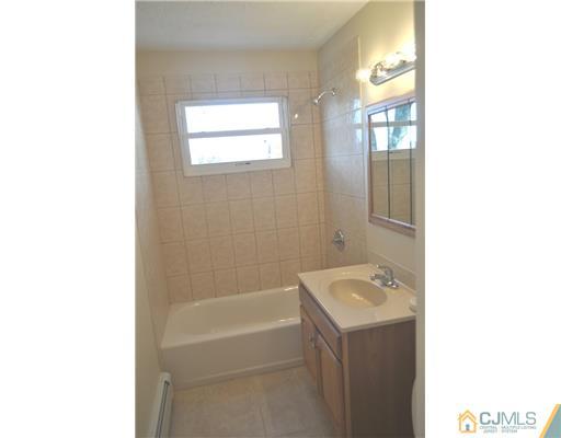 51 Farmingdale Road Fords, NJ 08863 - Photo 4 of 6 a bathroom with a tub sink vanity and a mirror