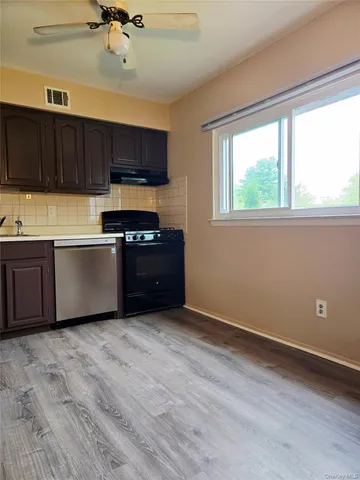 a kitchen with stainless steel appliances granite countertop a sink cabinets and wooden floor