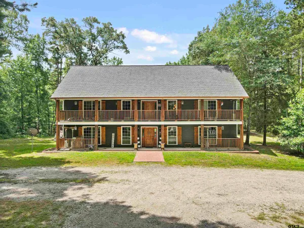 a front view of a house with a garden and trees