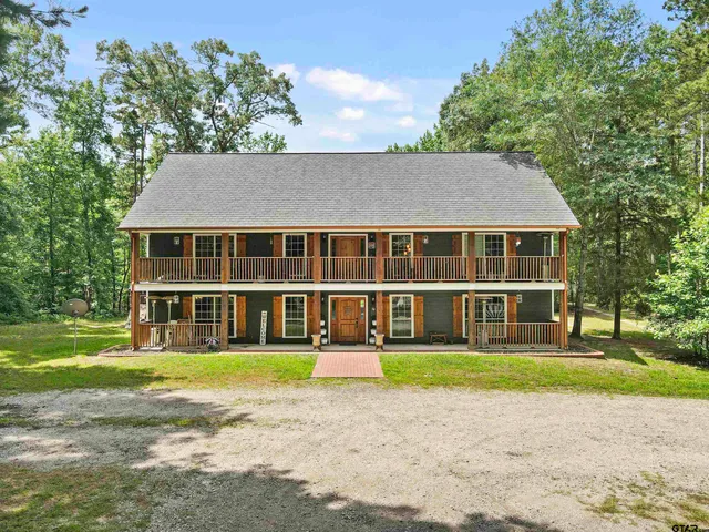 a front view of a house with a garden and trees
