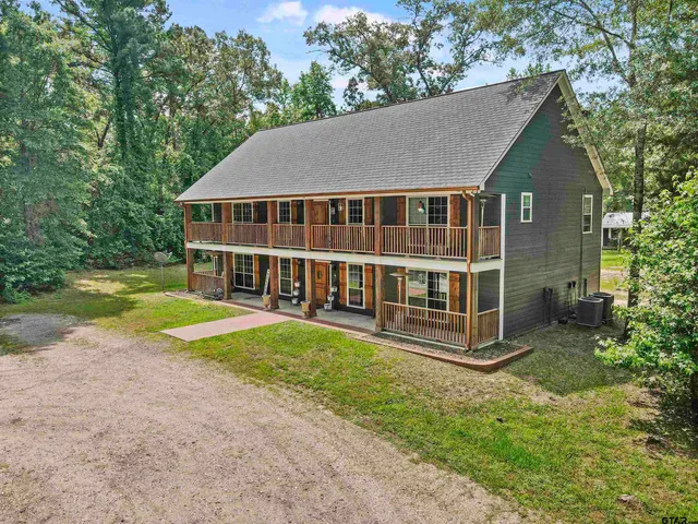 a backyard of a house with large trees and plants