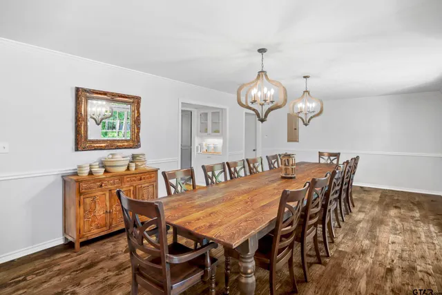 a view of a dining room and livingroom with furniture wooden floor a rug and a chandelier