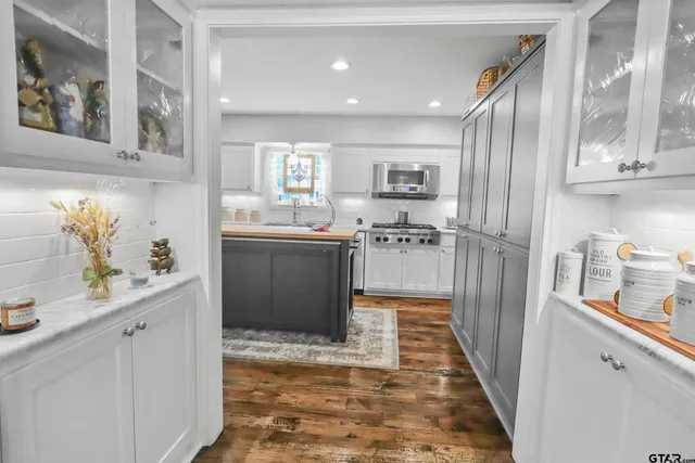 a kitchen with stainless steel appliances granite countertop a refrigerator a sink dishwasher and white cabinets with wooden floor