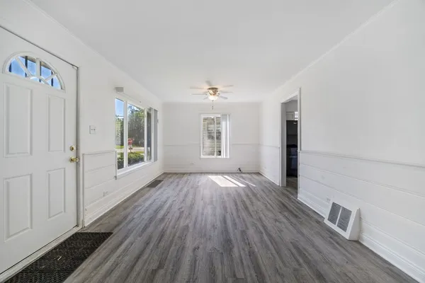 a view of an empty room with wooden floor and a window