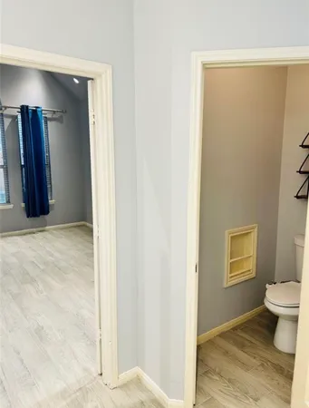 a view of a hallway with wooden floor and a bathroom
