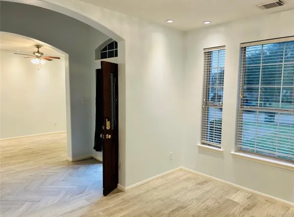 an empty room with wooden floor and windows
