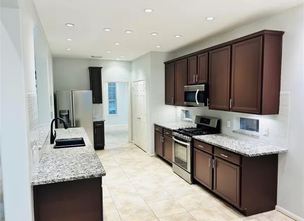 a kitchen with stainless steel appliances granite countertop a sink stove and refrigerator