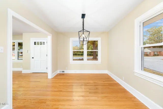 a view of an empty room with window and wooden floor