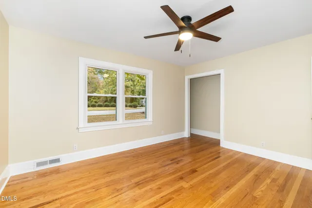 a view of an empty room with window and wooden floor