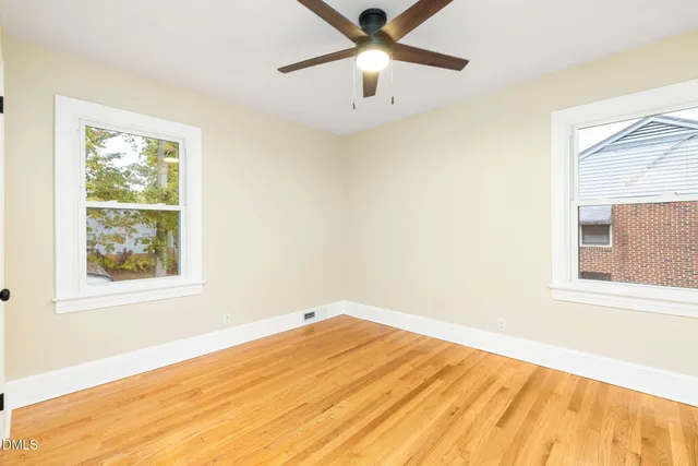 a view of an empty room with window and a ceiling fan