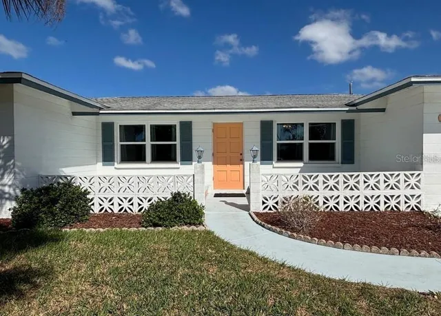 a view of a house with a large window and flower plants