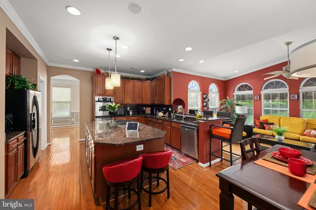 a dinning room with stainless steel appliances granite countertop a kitchen island furniture and a large window
