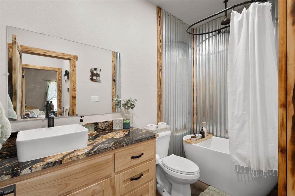 1501 Huddleston Road Sunset, TX 76270 - Photo 13 of 17 a bathroom with a granite countertop sink toilet a mirror and shower curtain