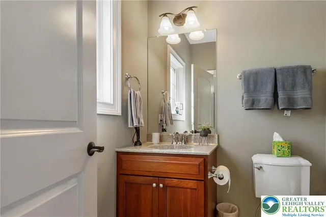 a bathroom with a granite countertop sink a toilet and mirror