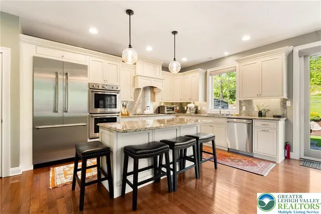 a kitchen with stainless steel appliances granite countertop a stove a sink a refrigerator a microwave a island with wooden floor and cabinets