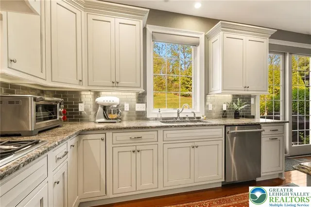 a kitchen with granite countertop white cabinets and stainless steel appliances