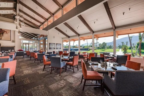 a room with lots of tables a large window and chairs