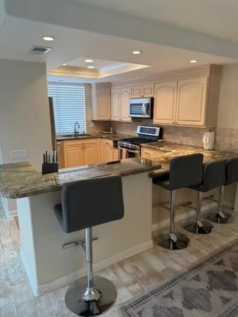 a kitchen with stainless steel appliances granite countertop a table chairs sink and cabinets