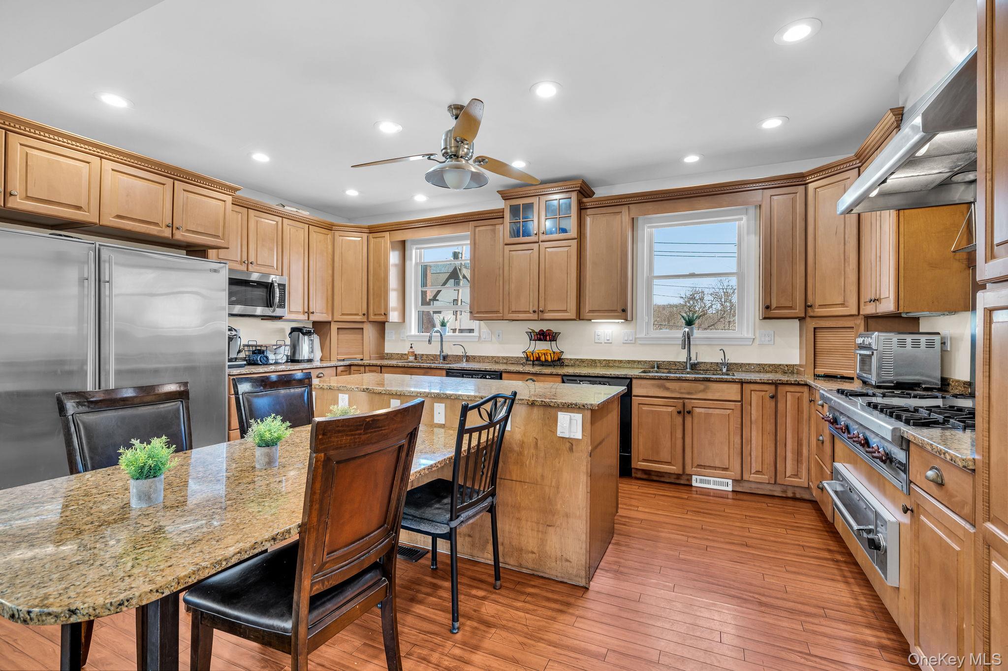 a kitchen with stainless steel appliances granite countertop a stove top oven a sink dishwasher a dining table and chairs with wooden floor