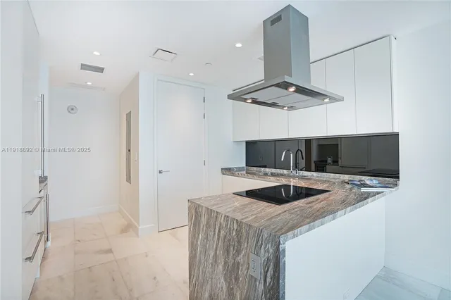 a kitchen with stainless steel appliances kitchen island granite countertop a refrigerator and a sink