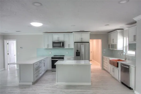 a large kitchen with stainless steel appliances lots of counter space and wooden floors