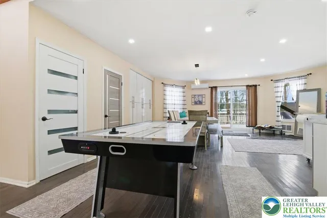 a large white kitchen with stainless steel appliances granite countertop a stove a sink a refrigerator and white cabinets with wooden floor