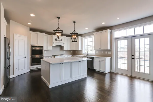 a kitchen with stainless steel appliances granite countertop wooden floors and white cabinets
