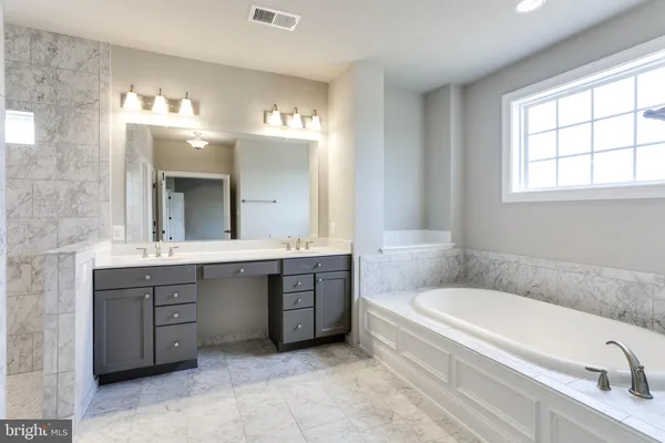 a bathroom with a granite countertop bathtub a sink and a large mirror