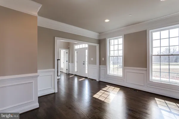 an empty room with wooden floor and windows with curtains