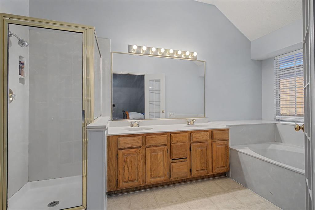 645 Cross Ridge Circle Fort Worth, TX 76120 - Photo 19 of 26 Ensuite bathroom featuring double vanity, a bath, lofted ceiling, a stall shower, and light tile patterned flooring