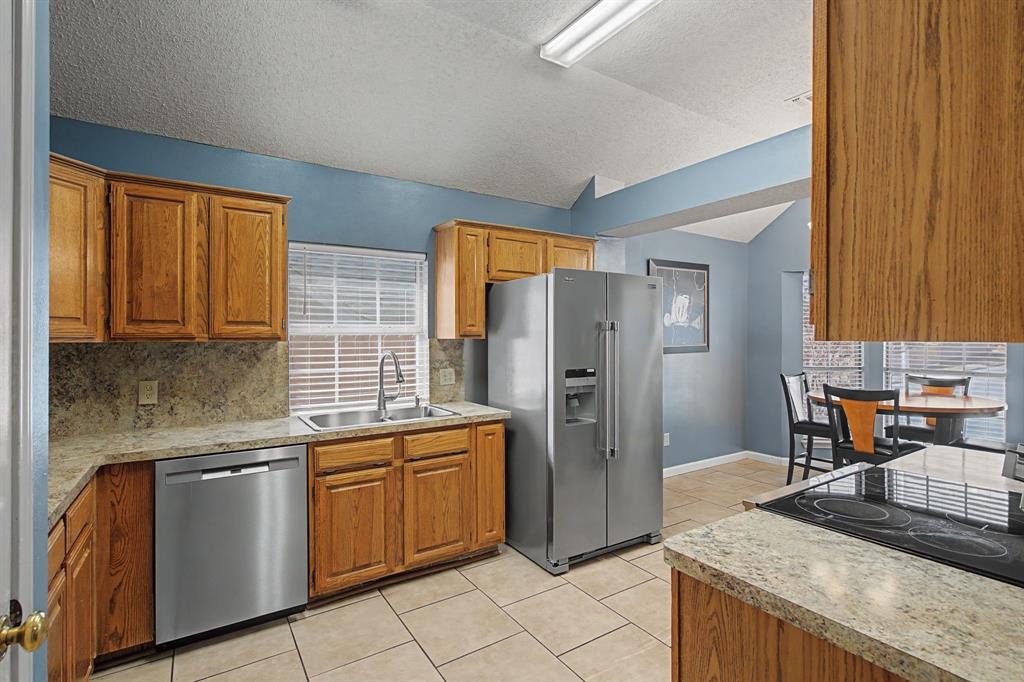 645 Cross Ridge Circle Fort Worth, TX 76120 - Photo 6 of 26 Kitchen featuring new stainless steel appliances, backsplash, wood finish cabinetry, and light tile patterned floors