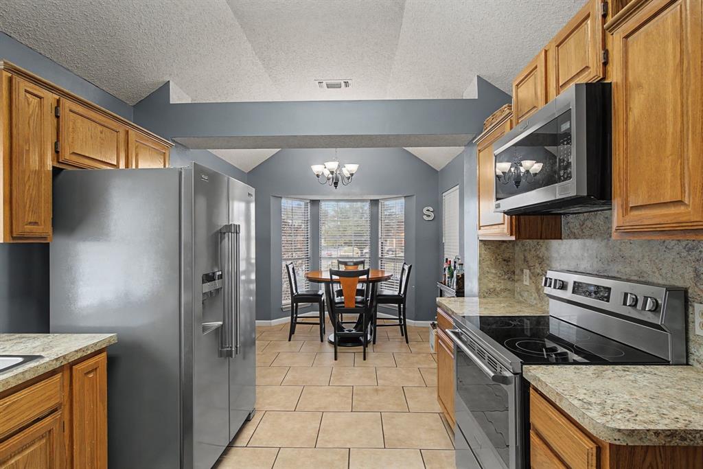 645 Cross Ridge Circle Fort Worth, TX 76120 - Photo 7 of 26 Kitchen featuring new stainless steel appliances, wood finish cabinetry, light tile patterned floors, and light countertops