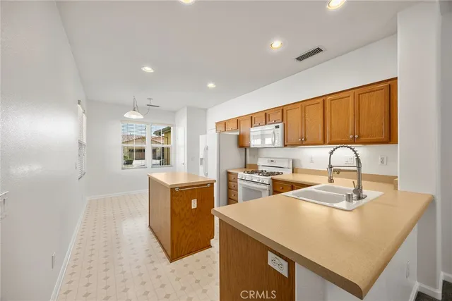 a kitchen with kitchen island a sink appliances and a counter top space