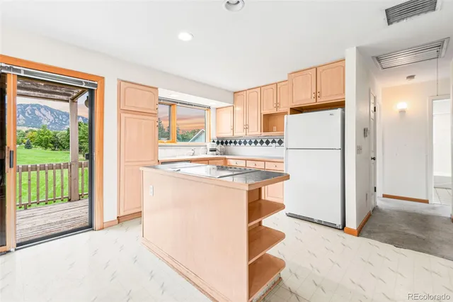 a kitchen with stainless steel appliances granite countertop a refrigerator a sink a stove and a refrigerator