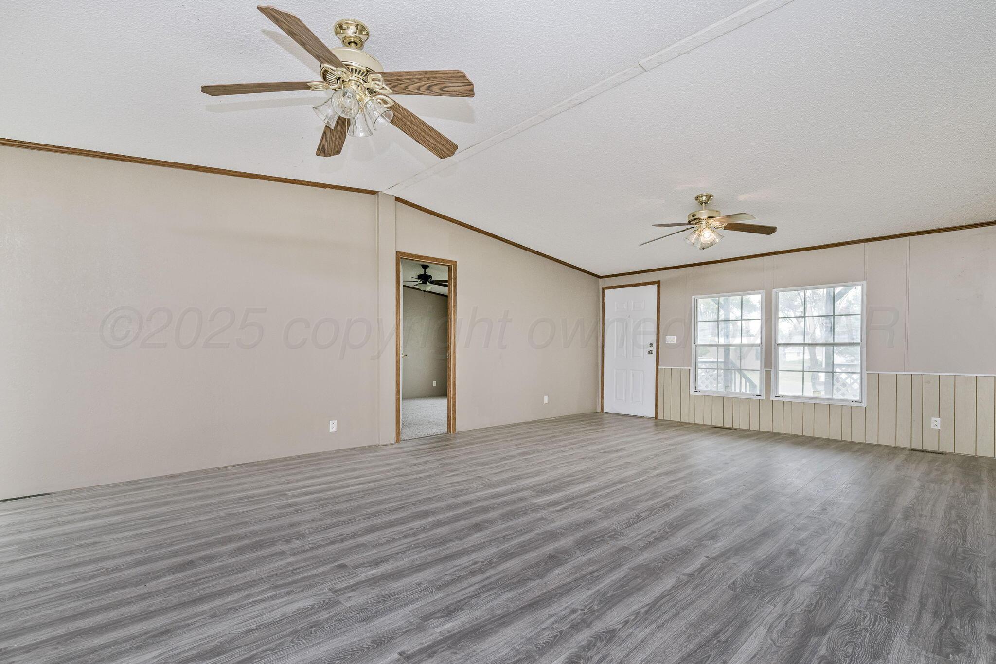 101 Collier Avenue Groom, TX 79039 - Photo 7 of 21 an empty room with wooden floor chandelier fan and windows
