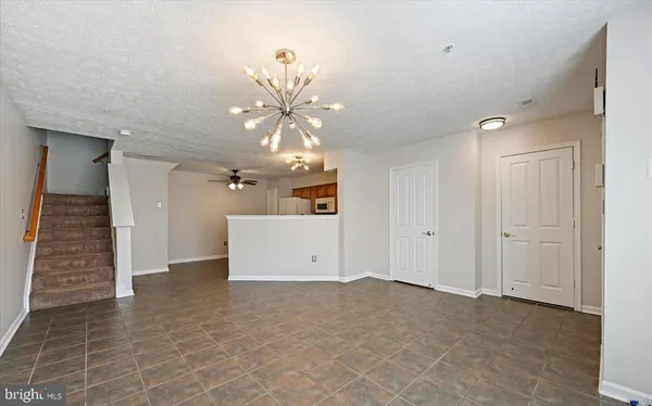 an empty room with a chandelier fan and windows