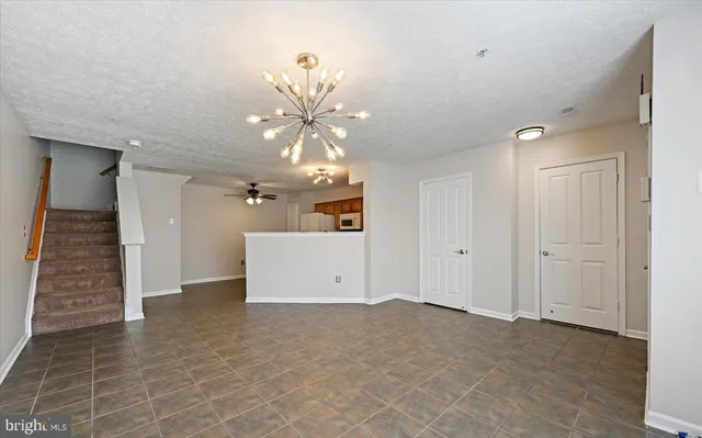 an empty room with a chandelier fan and windows