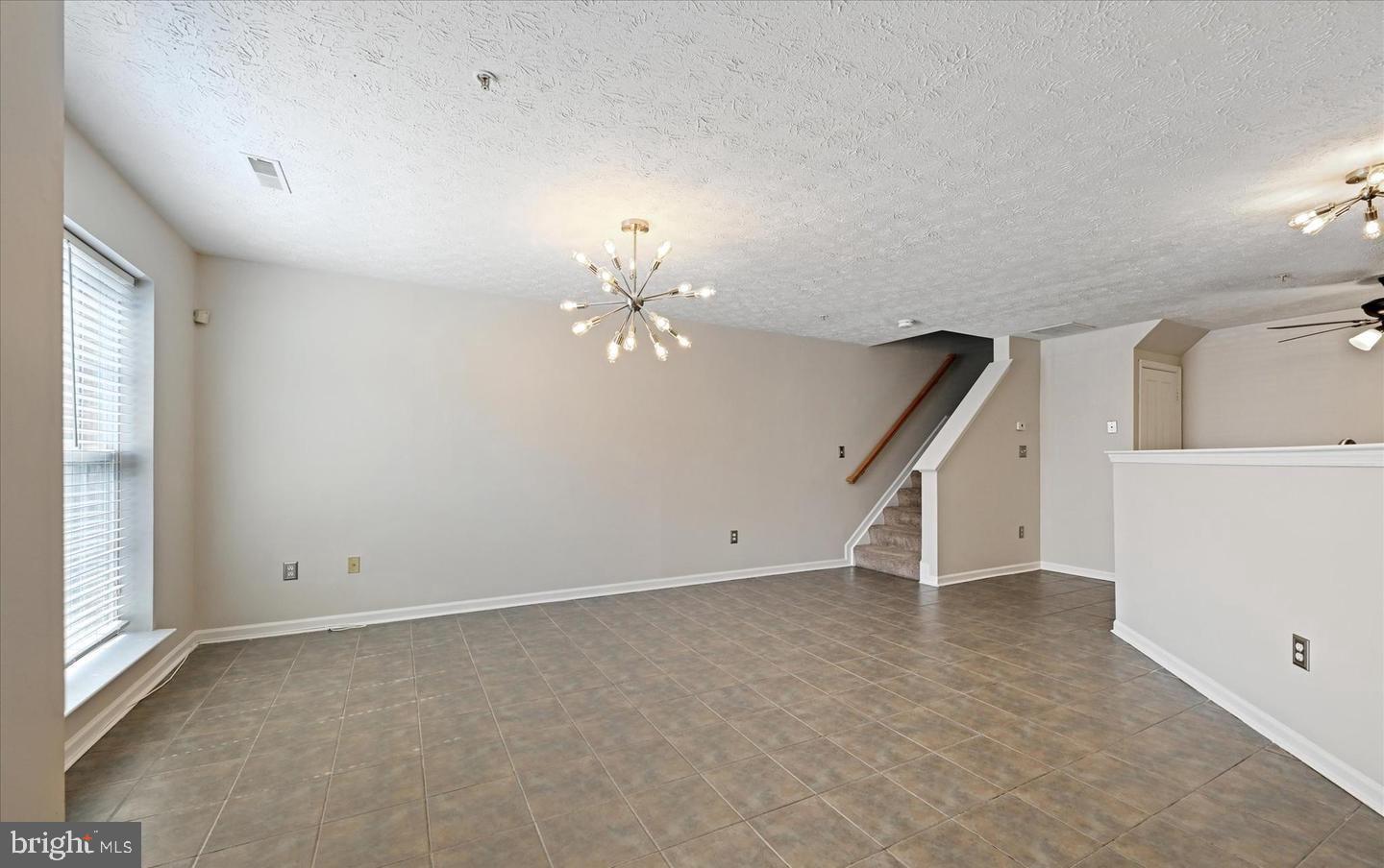 1817 Triple Feather Road Severn, MD 21144 - Photo 7 of 10 an empty room with a chandelier fan and windows