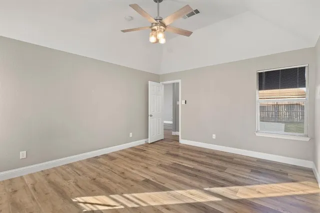 a view of an empty room with window and wooden floor