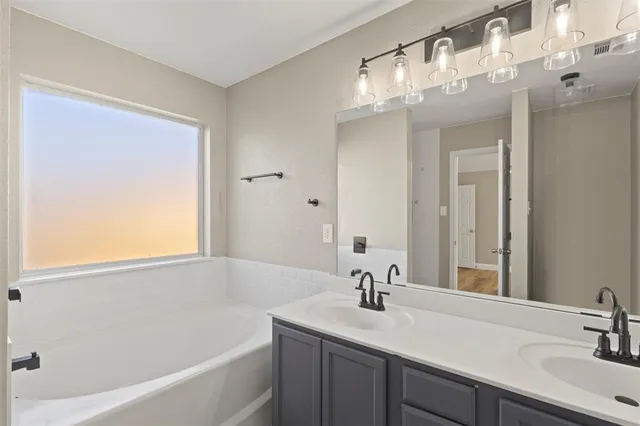 a bathroom with a sink a large mirror and a bathtub