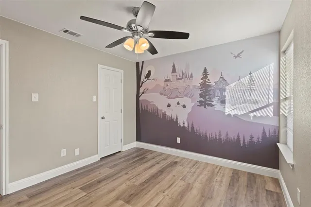 a view of a room with wooden floor and ceiling fan
