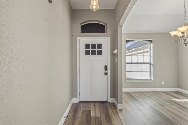 an empty room with wooden floor cabinet and windows