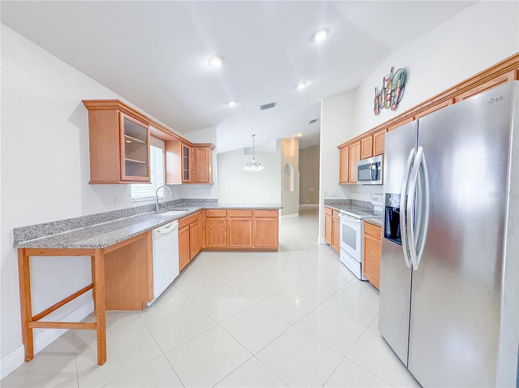 4150 Branchside Lane Wesley Chapel, FL 33543 - Photo 10 of 32 a large kitchen with stainless steel appliances kitchen island granite countertop a refrigerator and a sink